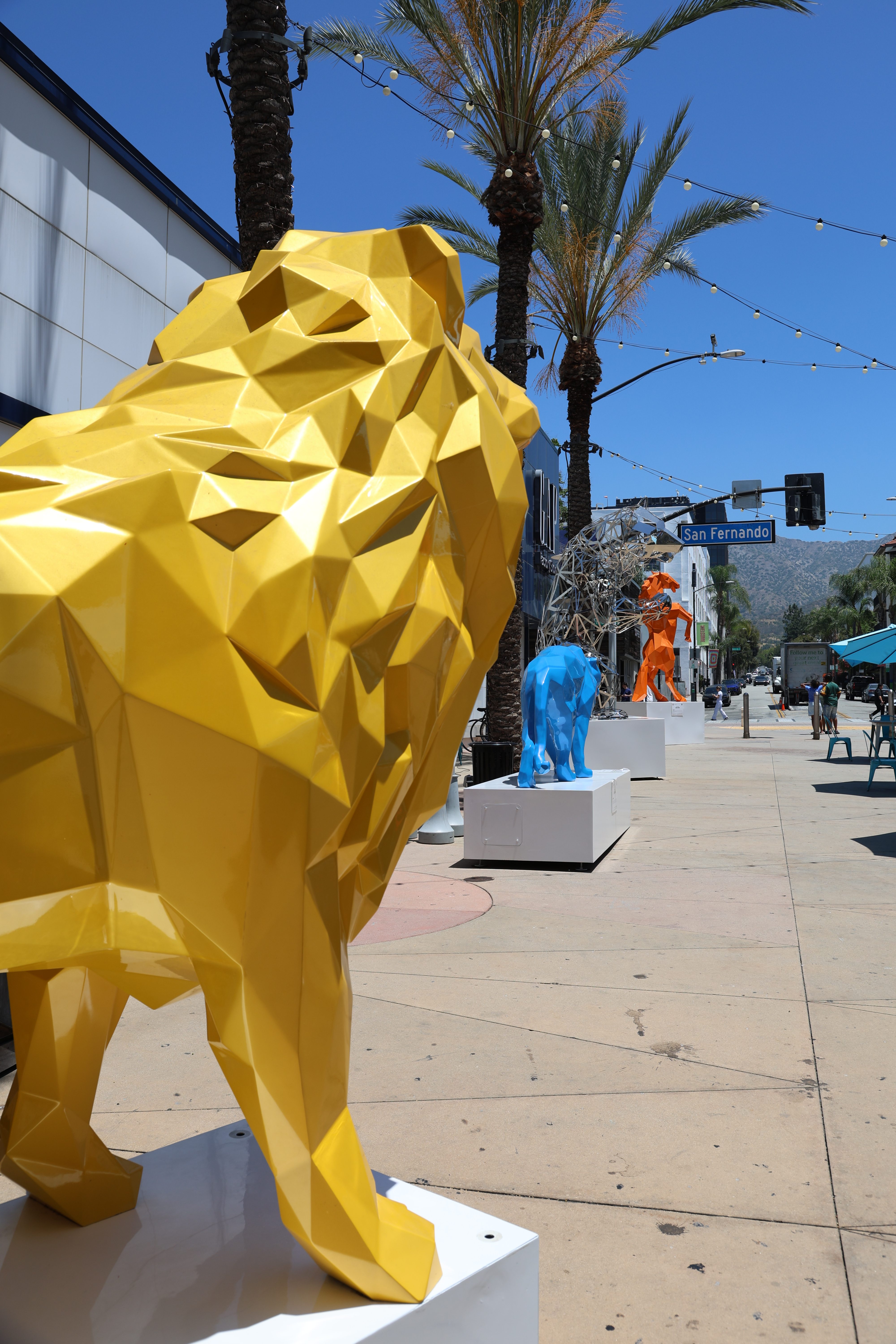Yellow lion sculpture with the full AMC Walkway and other sculptures visible behind